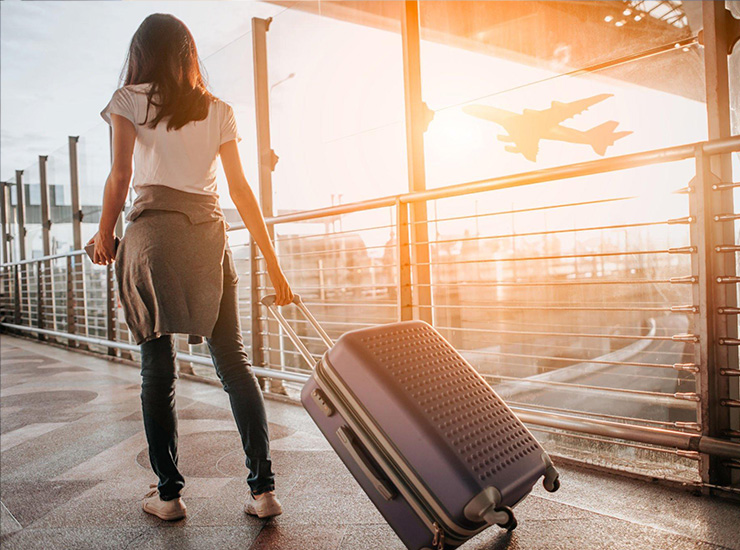 Young woman pulling suitcase in airport terminal